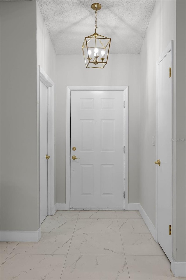 doorway with a chandelier and a textured ceiling