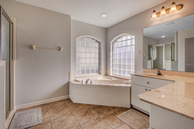 bathroom featuring plus walk in shower, a textured ceiling, tile patterned flooring, and vanity