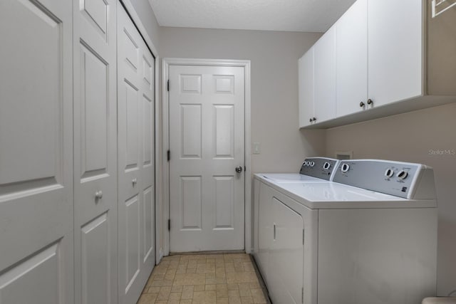 washroom with cabinets, a textured ceiling, and washing machine and dryer