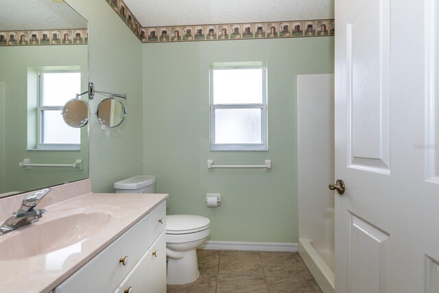 bathroom featuring toilet, vanity, baseboards, a shower, and tile patterned floors