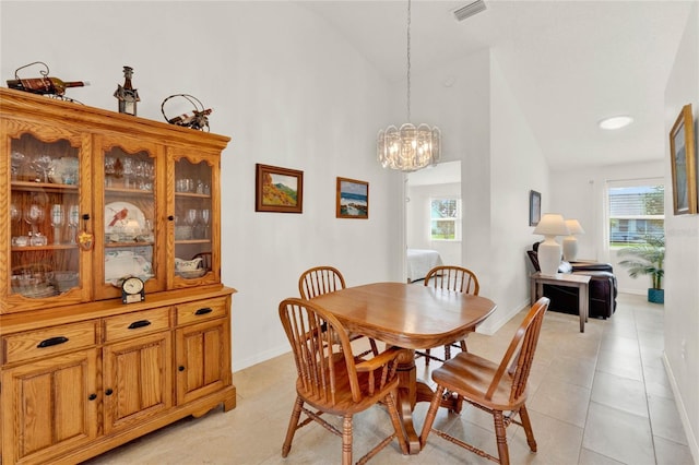 dining room with light tile patterned flooring, a healthy amount of sunlight, high vaulted ceiling, and a notable chandelier