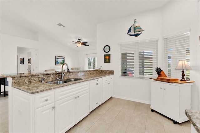 kitchen featuring kitchen peninsula, sink, white cabinets, white dishwasher, and light stone counters