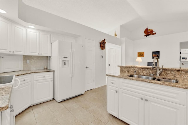 kitchen with white cabinetry, white fridge with ice dispenser, sink, and light stone counters