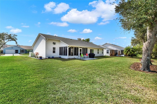 rear view of property featuring a sunroom, a patio area, and a lawn