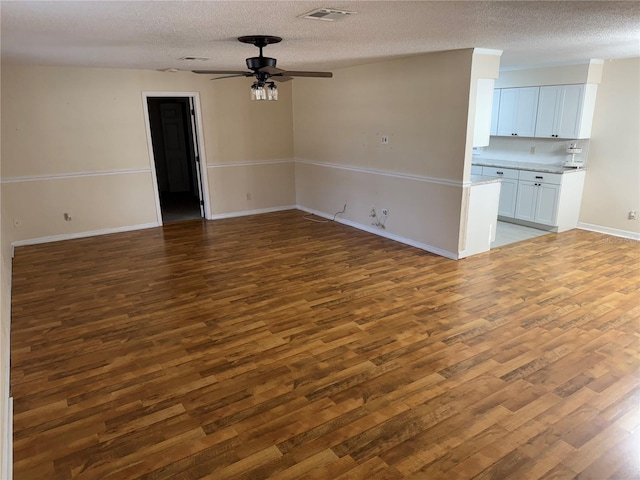 unfurnished living room featuring a textured ceiling, ceiling fan, and dark hardwood / wood-style floors