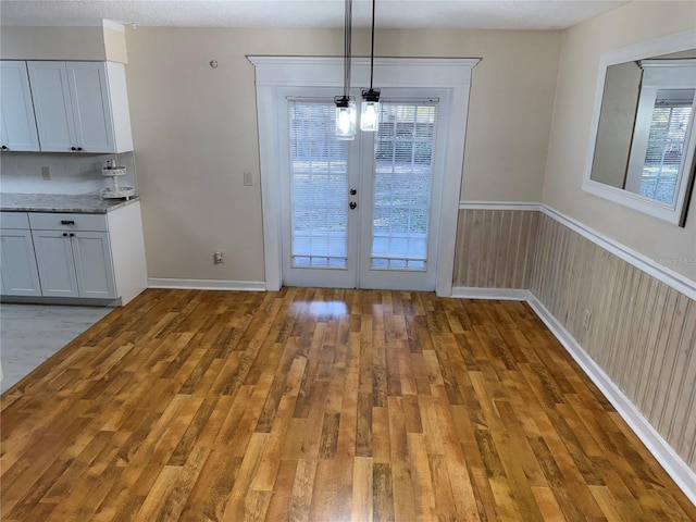 unfurnished dining area featuring french doors and light hardwood / wood-style flooring