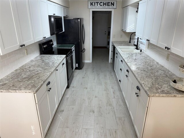 kitchen with tasteful backsplash, electric range, white cabinets, light hardwood / wood-style flooring, and sink