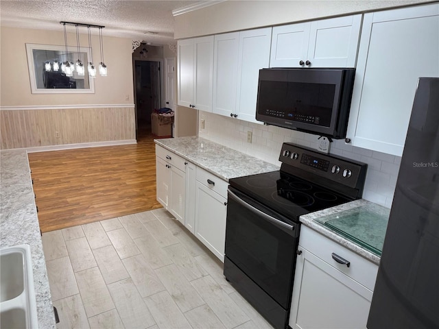 kitchen with white cabinetry, hanging light fixtures, a textured ceiling, light stone counters, and black appliances