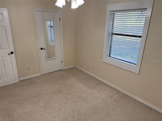 unfurnished room with light carpet and a notable chandelier