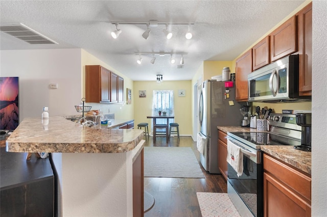 kitchen featuring dark hardwood / wood-style flooring, stainless steel appliances, a kitchen breakfast bar, and a textured ceiling