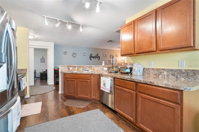 kitchen featuring appliances with stainless steel finishes, sink, kitchen peninsula, dark wood-type flooring, and a textured ceiling