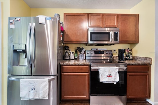 kitchen featuring stainless steel appliances, a textured ceiling, and dark stone countertops