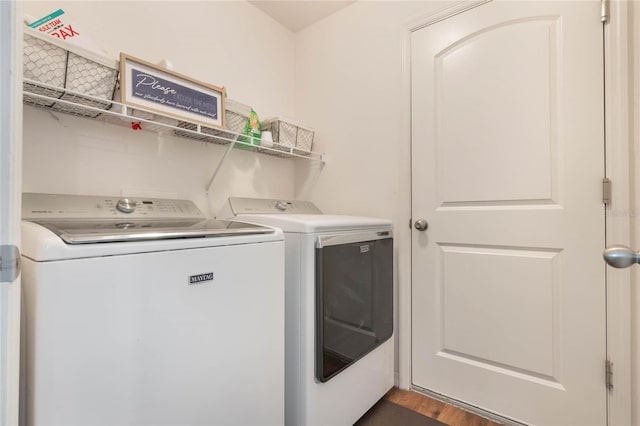 clothes washing area with dark wood-type flooring and washer and clothes dryer