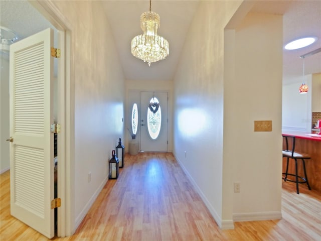 entrance foyer with lofted ceiling, a chandelier, and light wood-type flooring