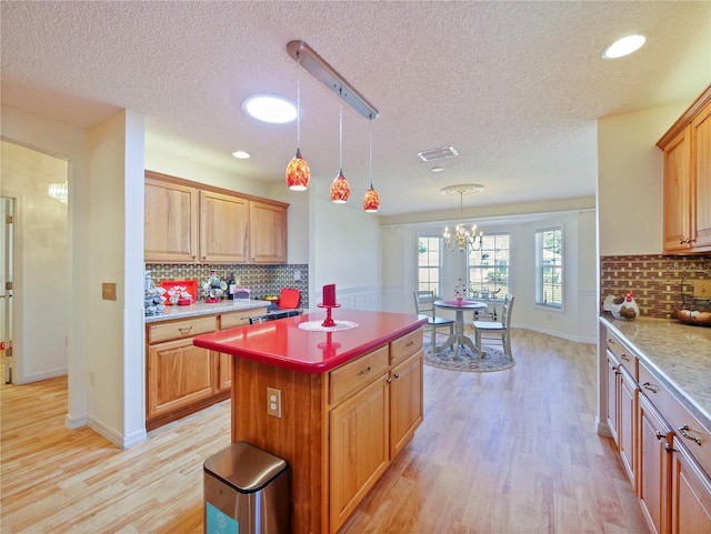 kitchen with tasteful backsplash, decorative light fixtures, a textured ceiling, light wood-type flooring, and a kitchen island