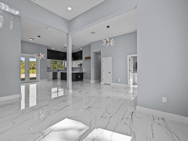 unfurnished living room with ceiling fan, a high ceiling, and french doors