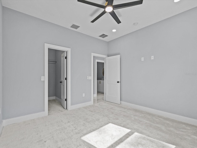 unfurnished bedroom featuring ceiling fan, light colored carpet, a closet, and a spacious closet