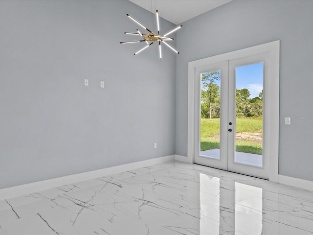 spare room with french doors and an inviting chandelier