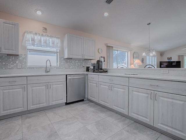 kitchen featuring white cabinetry, lofted ceiling, dishwasher, hanging light fixtures, and sink