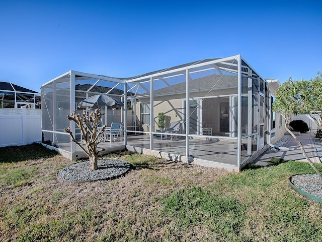 rear view of property with a lawn, a patio area, and glass enclosure