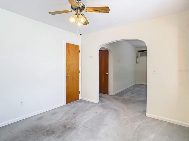 unfurnished room with ceiling fan and a wall unit AC