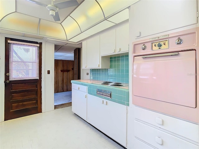 kitchen featuring tasteful backsplash, white electric stovetop, oven, and white cabinets