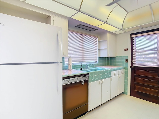 kitchen featuring tasteful backsplash, dishwasher, white cabinetry, sink, and white refrigerator