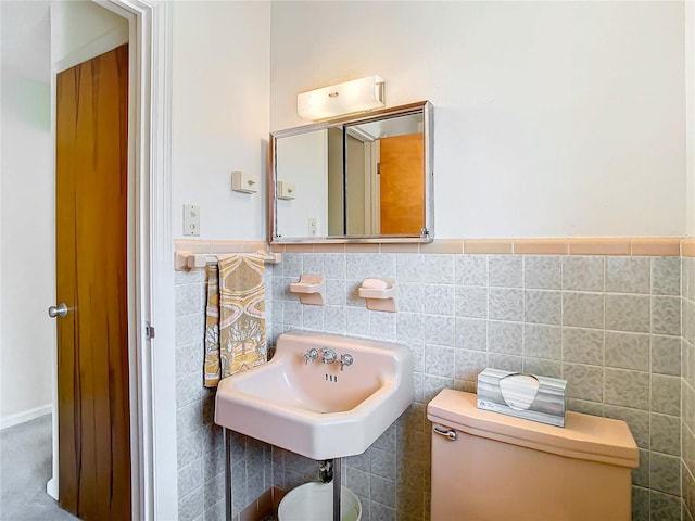 bathroom with tile walls, sink, and toilet