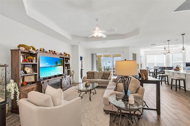 5857 Mackenzie Ave, The Villages, FL 32163 - living room with a tray ceiling, visible vents, ceiling fan with notable chandelier, and wood finished floors