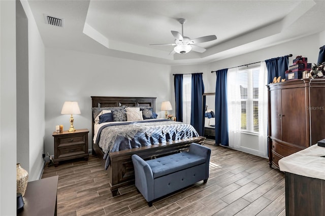 5857 Mackenzie Ave, The Villages, FL 32163 - bedroom featuring visible vents, baseboards, wood finish floors, a ceiling fan, and a tray ceiling