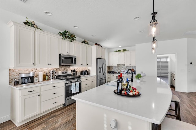 5857 Mackenzie Ave, The Villages, FL 32163 - kitchen featuring a breakfast bar, wood finished floors, stainless steel appliances, tasteful backsplash, and a sink