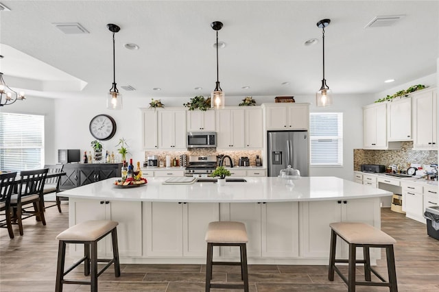 5857 Mackenzie Ave, The Villages, FL 32163 - kitchen featuring dark wood finished floors, visible vents, white cabinets, and appliances with stainless steel finishes
