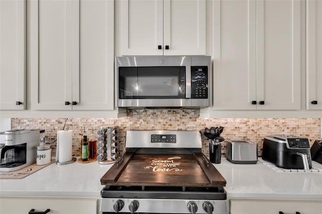 5857 Mackenzie Ave, The Villages, FL 32163 - kitchen with white cabinetry, backsplash, light countertops, and appliances with stainless steel finishes