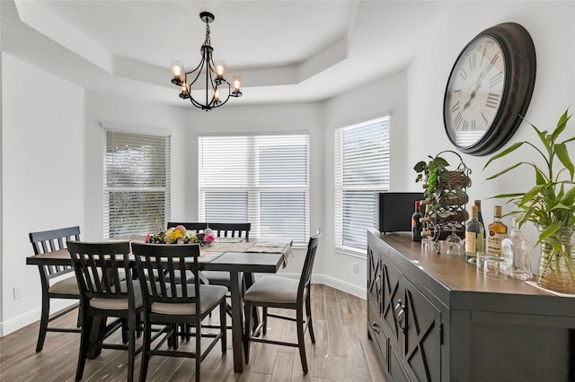 5857 Mackenzie Ave, The Villages, FL 32163 - dining space featuring baseboards, wood finished floors, a chandelier, and a raised ceiling
