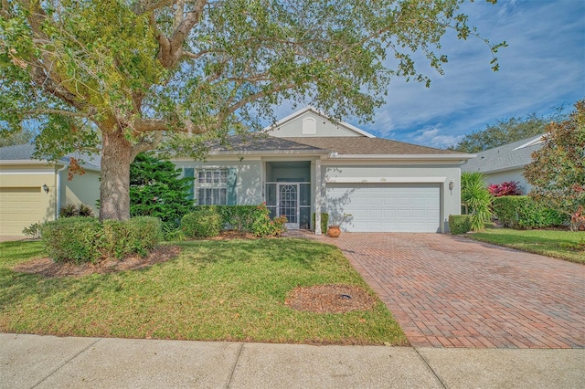 single story home featuring decorative driveway, an attached garage, a front yard, and stucco siding