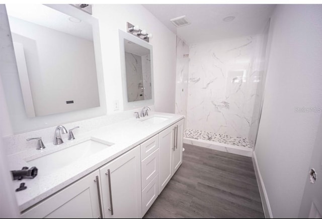 bathroom featuring hardwood / wood-style flooring, vanity, and tiled shower