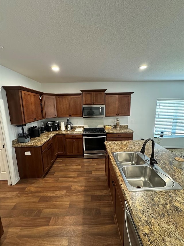 kitchen with stainless steel appliances, dark hardwood / wood-style floors, sink, and a textured ceiling