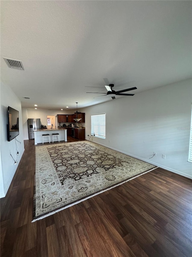 unfurnished living room with dark hardwood / wood-style floors and ceiling fan