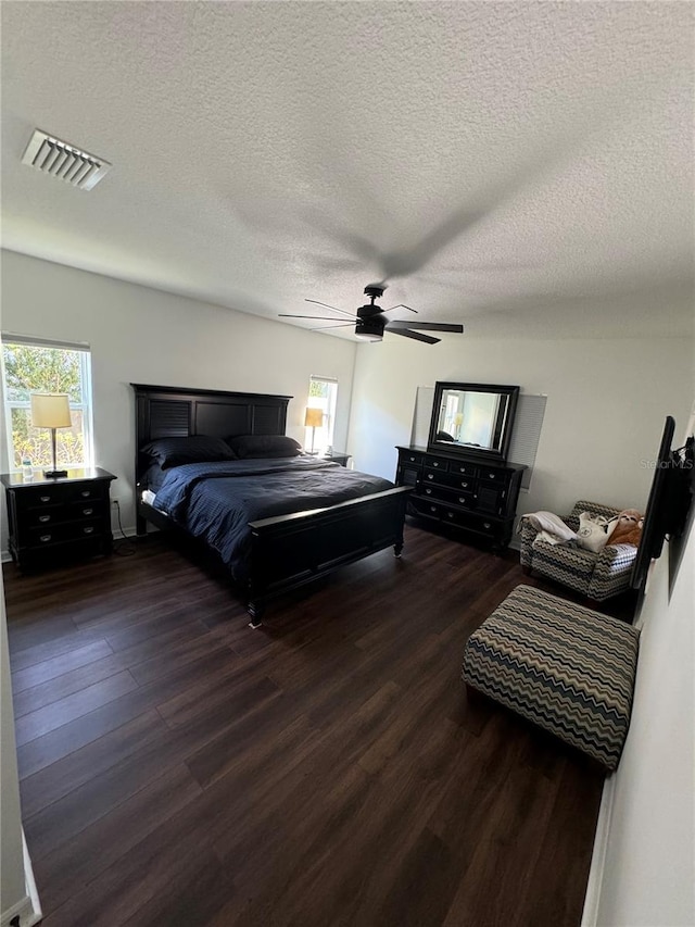 bedroom featuring multiple windows, ceiling fan, a textured ceiling, and dark hardwood / wood-style flooring