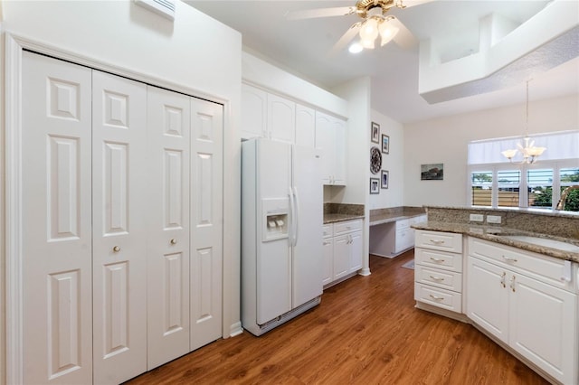 kitchen featuring white cabinetry, light wood-type flooring, dark stone counters, white refrigerator with ice dispenser, and sink