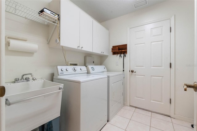 laundry room with cabinets, light tile patterned floors, separate washer and dryer, and sink