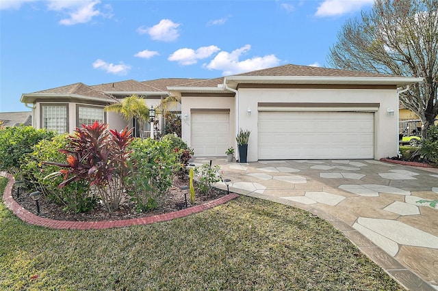 view of front of home with a garage, driveway, a front yard, and stucco siding