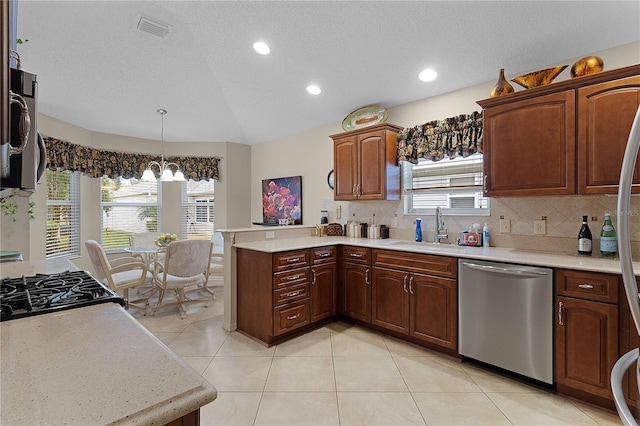 kitchen with appliances with stainless steel finishes, decorative light fixtures, decorative backsplash, sink, and kitchen peninsula