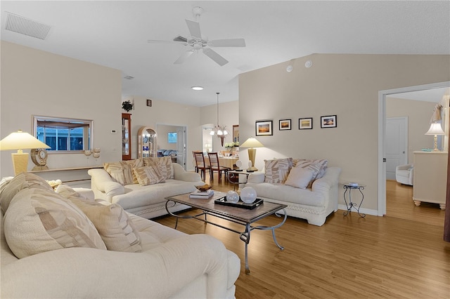 living room featuring hardwood / wood-style flooring, ceiling fan with notable chandelier, and vaulted ceiling