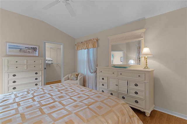 bedroom with a spacious closet, hardwood / wood-style floors, lofted ceiling, a closet, and ceiling fan