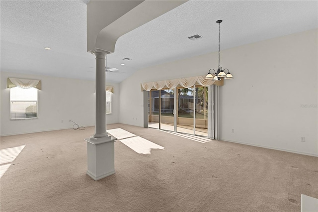 unfurnished living room with light carpet, lofted ceiling, a textured ceiling, and ornate columns