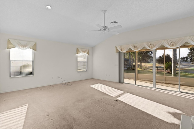 carpeted empty room with lofted ceiling, ceiling fan, and a textured ceiling