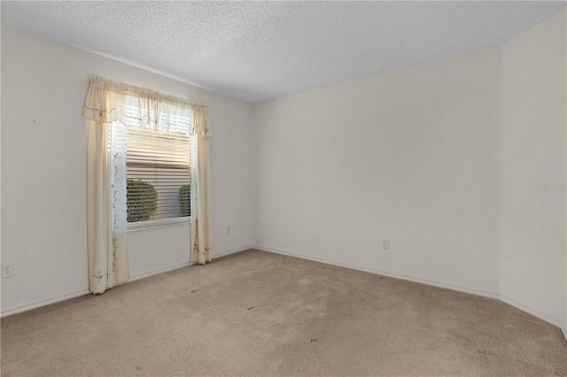 spare room featuring light carpet and a textured ceiling