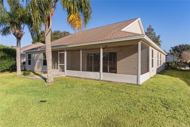 back of property with ceiling fan, a yard, and a sunroom