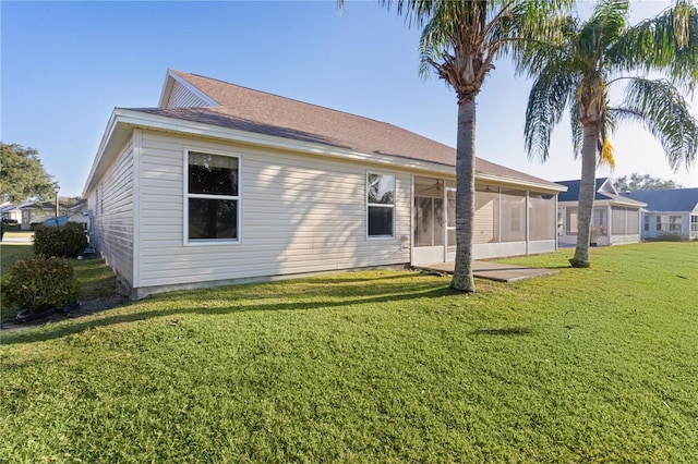 rear view of house featuring a sunroom and a lawn